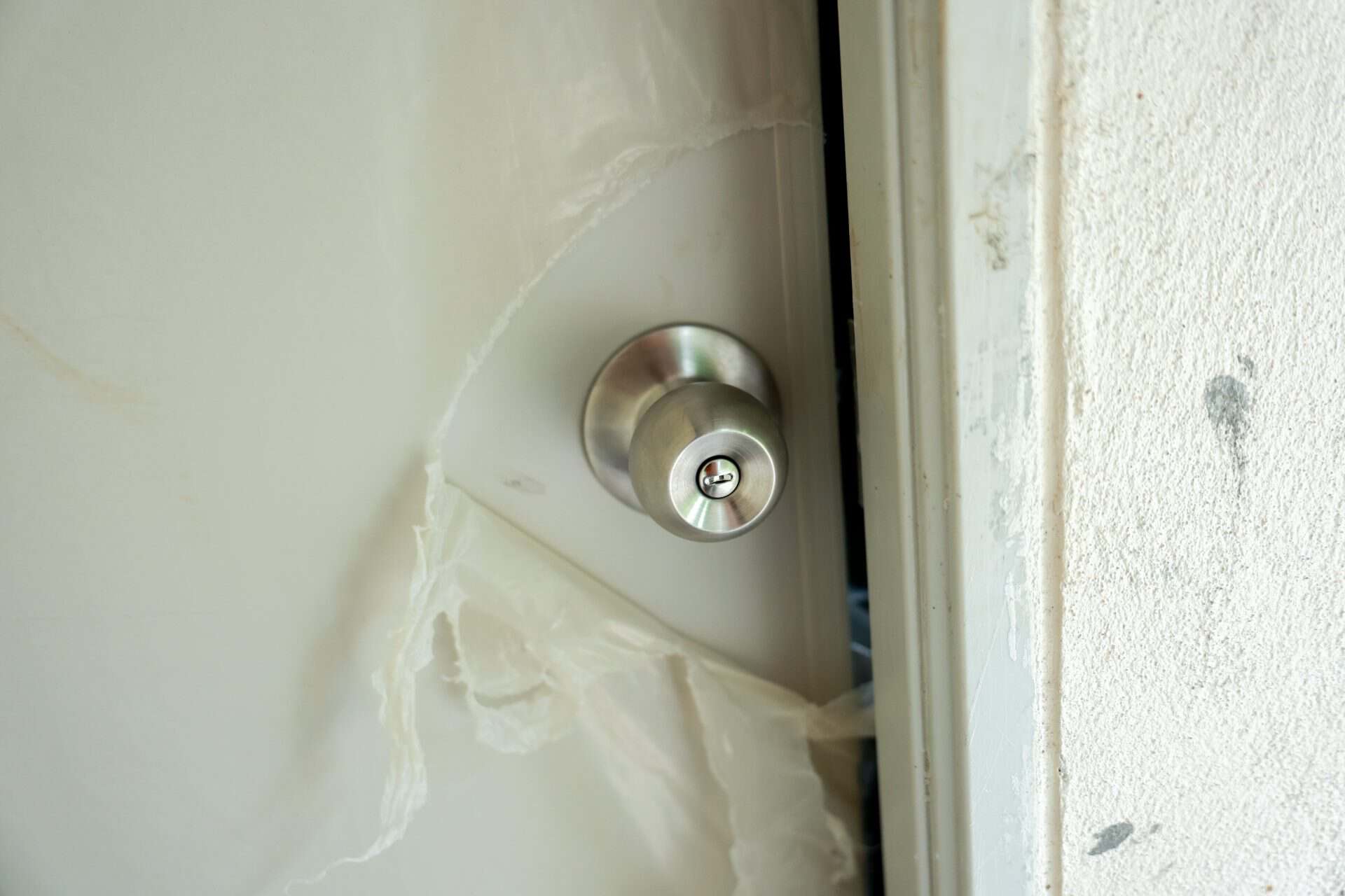 A broken door damaged lock white wall security issue vandalism close up metal knob home safety forced entry destruction stress